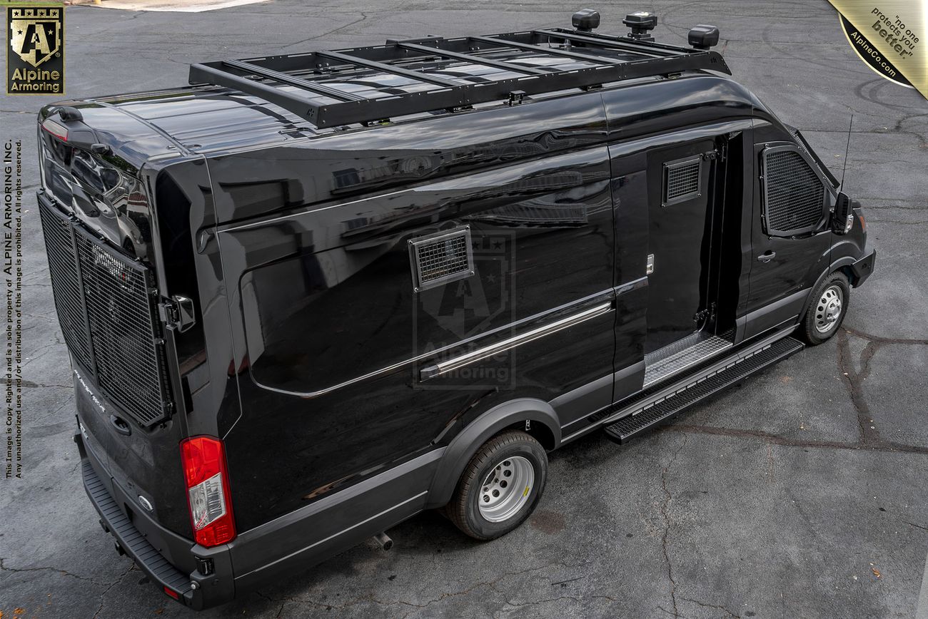A black Pointer van with its rear doors open, revealing organized interior equipment. The van is parked on a paved surface with green foliage in the background.