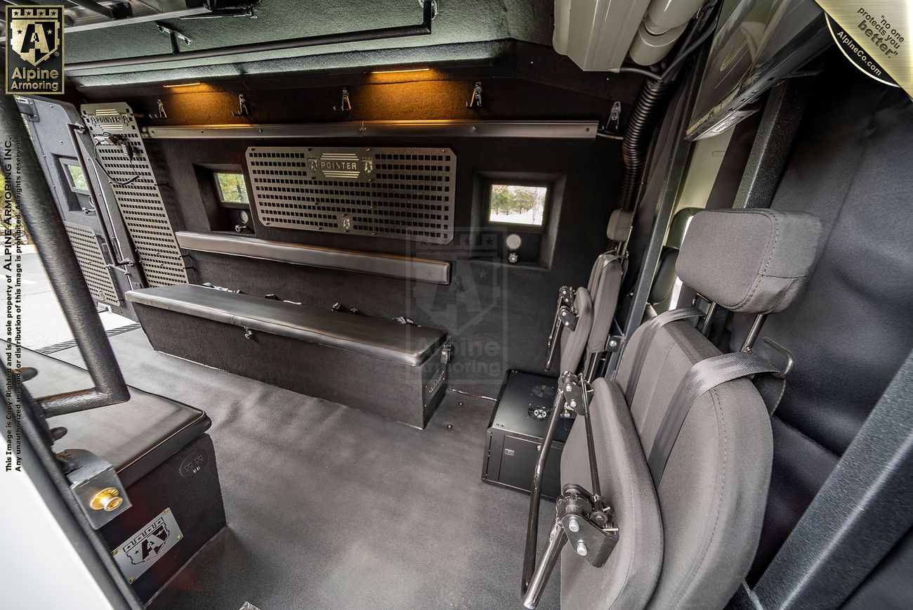 Interior of a police Pointer van showing benches, seats, and compartments, outfitted with equipment for transportation and operational use.