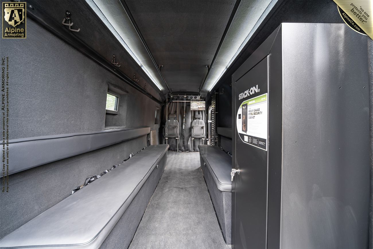 Interior of an armored Sprinter from Alpine Armoring with bench seating and secure compartments, designed for SWAT or tactical use.