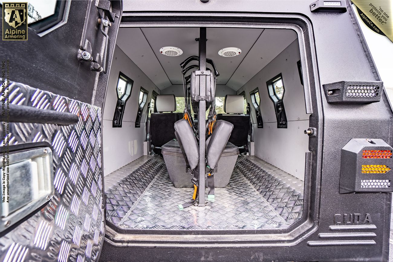 Open rear view of a bulletproof CUDA's interior showing metal flooring, bench seats along the sides, and a central mount for equipment.